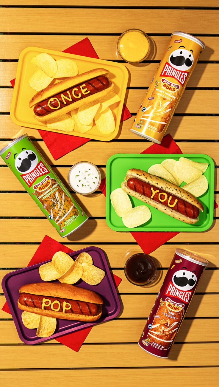 Video thumbnail, Three trays of hot dogs and chips are paired with Pringles Pop Dog Buns cans in honey mustard, sour cream and onion, and BBQ flavors.
